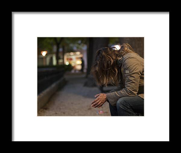 Problems Framed Print featuring the photograph Young woman sitting on a bench looking down at night by Carlos Ciudad Photos