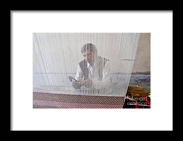 Carpet Weaving Framed Print featuring the photograph A weaver weaves a carpet. by Elena Perelman