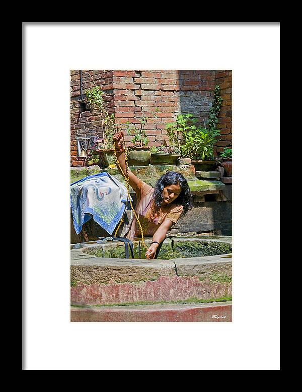 Well Framed Print featuring the photograph A woman draws water at a well in Bhaktapur Nepal by Christopher Byrd