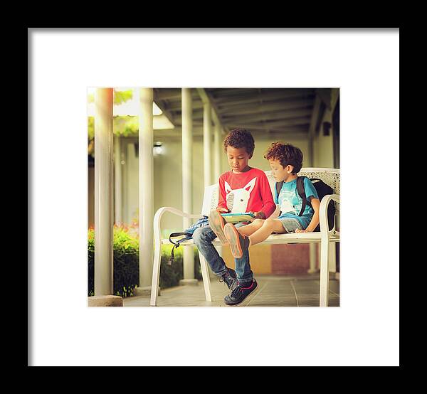 Playing Framed Print featuring the photograph Anerican boy play game in tablet togather in the park by Anek Suwannaphoom