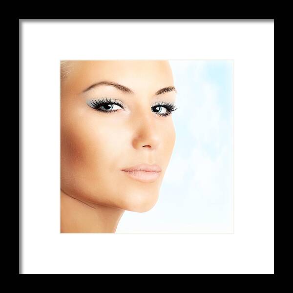 Abstract Framed Print featuring the photograph Beautiful female face over abstract blue sky background by Anna Om