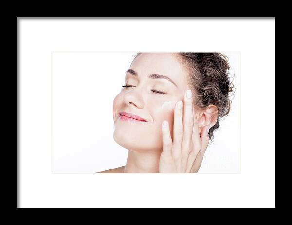 Skincare Framed Print featuring the photograph Beautiful young woman smiling and applying eye cream. by Michal Bednarek