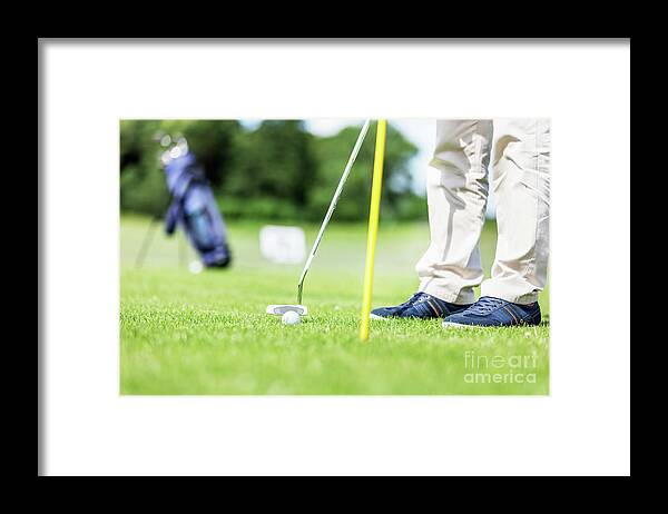 Golf Framed Print featuring the photograph Golfer putting ball in the hole on a golf course. by Michal Bednarek