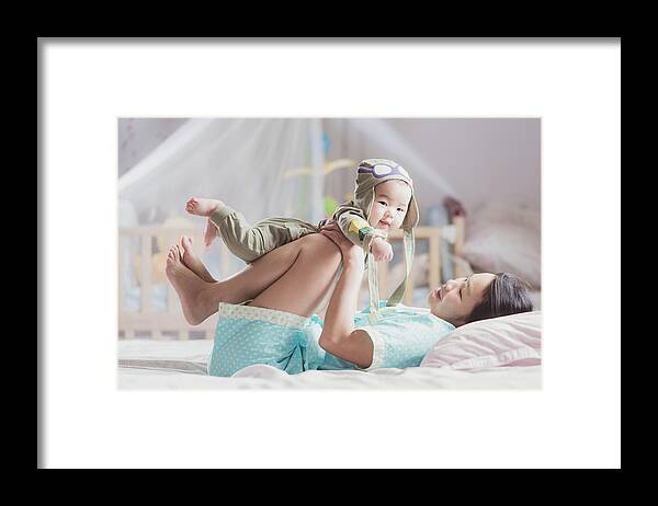 Baby Framed Print featuring the photograph Mother play with her baby after walkup on the bed in bedroom by Anek Suwannaphoom