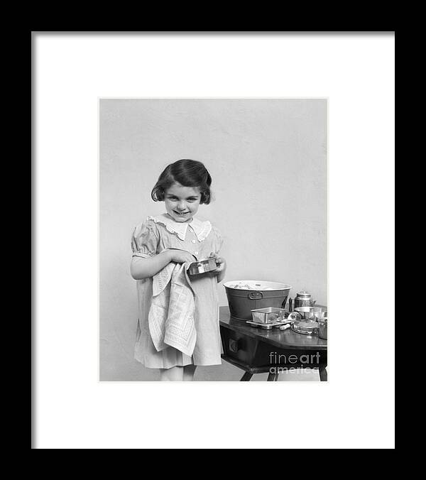 Alone Framed Print featuring the photograph Smiling Girl Drying Toy Pots, C.1930-40s by H. Armstrong Roberts/ClassicStock