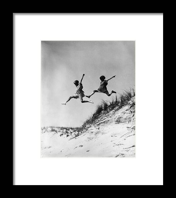1920s Framed Print featuring the photograph Two Girls Leaping Off Sand Dune by H Armstrong Roberts and ClassicStock