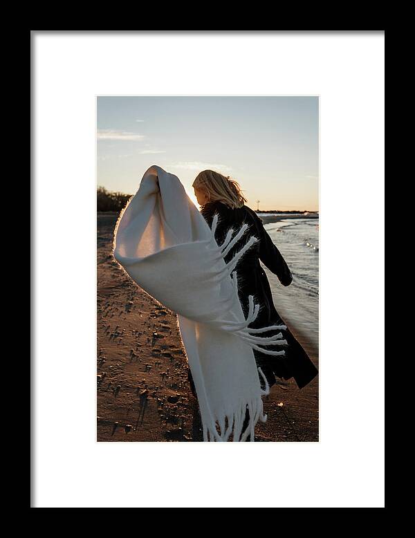 Young Girl Framed Print featuring the photograph A Young Girl Runs Along The Beach And The Scarf On Her Coat Develops. #1 by Cavan Images / Oleh Tiurkin