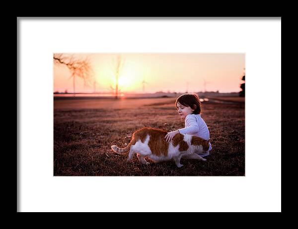 Everyday Chidhood Framed Print featuring the photograph A Small Young Boy Petting His Cat by Cavan Images