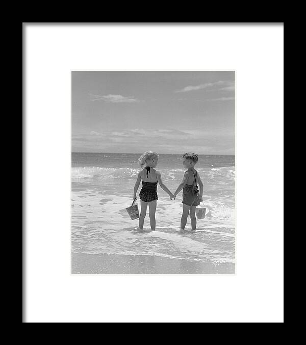 Water's Edge Framed Print featuring the photograph Boy And Girl Standing On Beach, Holding by H. Armstrong Roberts