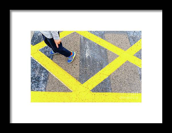 Asphalt Framed Print featuring the photograph Child's legs on yellow lines on asphalt. by Joaquin Corbalan