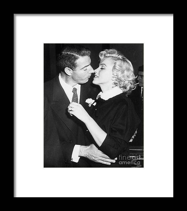 Following Framed Print featuring the photograph Joe Dimaggio And Marilyn Monroe Kiss by Bettmann