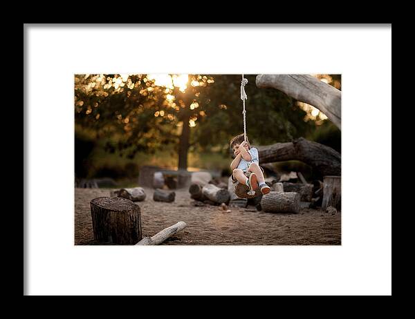 Boy Framed Print featuring the photograph Playful Boy Swinging On Rope Swing At Park by Cavan Images