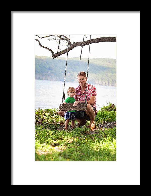 Father Framed Print featuring the photograph Portrait Of Father And Son Holding Rope Swing At Lakeshore by Cavan Images
