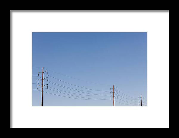 In A Row Framed Print featuring the photograph Power Lines Against A Clear Sky by Patrick Strattner