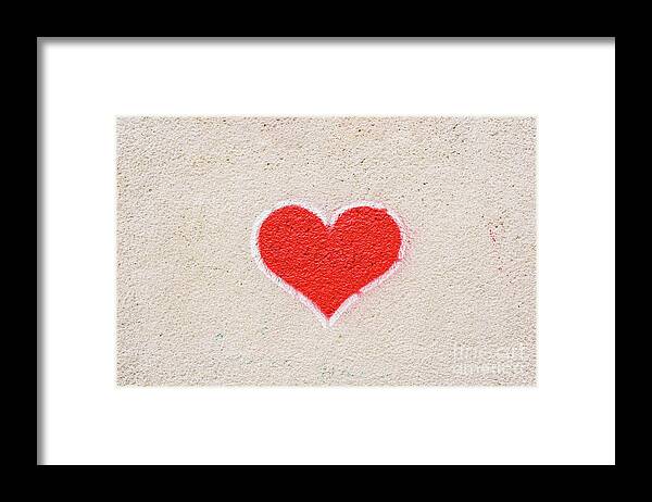 Abstract Framed Print featuring the photograph Red heart painted on a wall, message of love. by Joaquin Corbalan