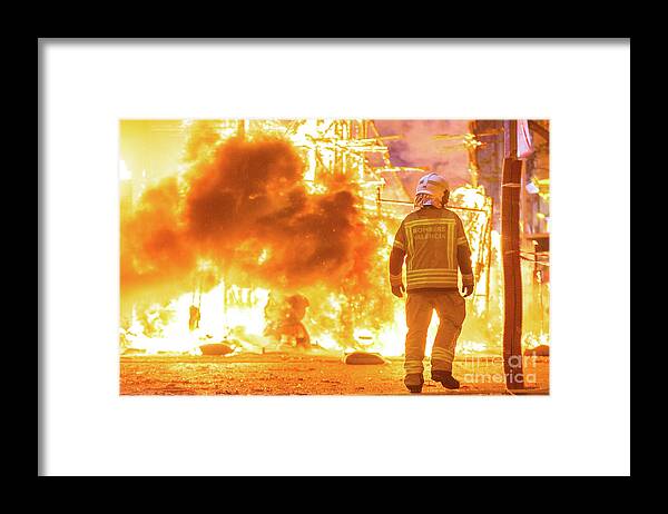 Background Framed Print featuring the photograph Silhouette of fireman trying to control a fire in a street durin by Joaquin Corbalan