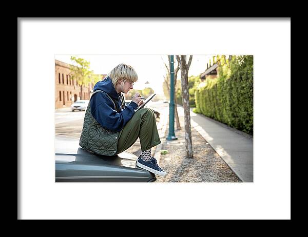Young Adult Framed Print featuring the photograph Young Adult Sitting On Hood Of Truck Using Stylus And Tablet To Work by Cavan Images