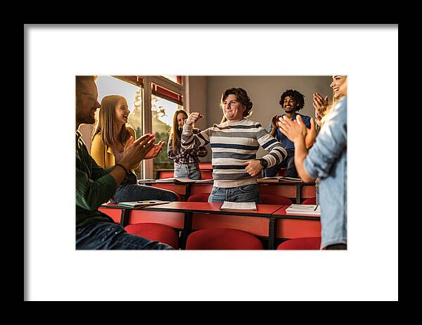 University Framed Print featuring the photograph Young students applauding their friend in the classroom. #1 by Skynesher