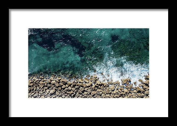 Seascape Framed Print featuring the photograph Aerial view from flying drone of crystal blue ocean water and sea wall. by Michalakis Ppalis