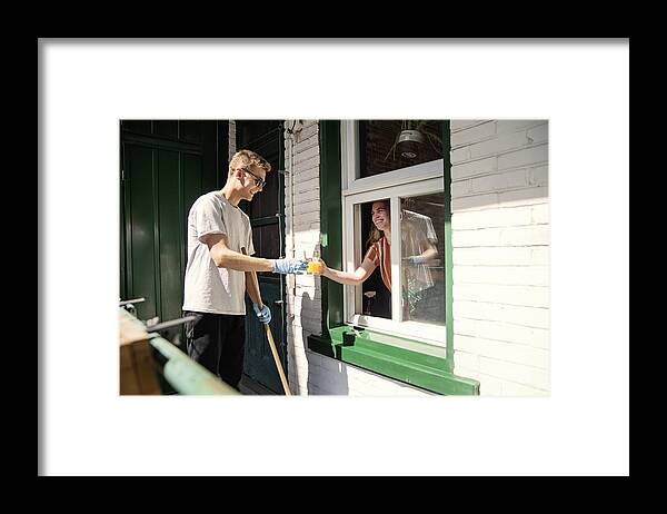 Young Men Framed Print featuring the photograph Millenial couple cleaning city balcony in spring. #4 by Martinedoucet