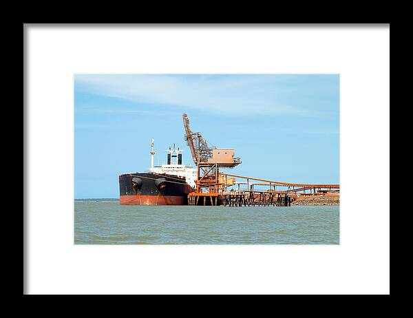 Bauxite Framed Print featuring the photograph A 254 meter Ore Carrier Ship unloading Bauxite at Gladstone Harbour, Queensland, Australia. by Geoff Childs
