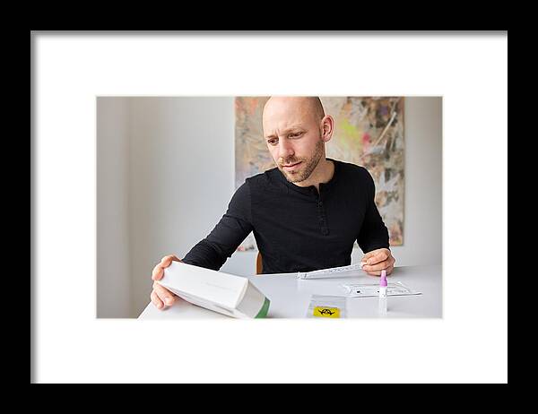 People Framed Print featuring the photograph A Man Reads The Package Or Operating Instructions For An Antigen Test Or Corona Rapid Test by 2K Studio