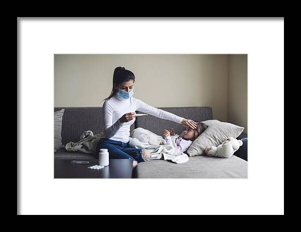 Cold And Flu Framed Print featuring the photograph A Mother Measure Temperature On Her Sick Child At Home. by ArtistGNDphotography