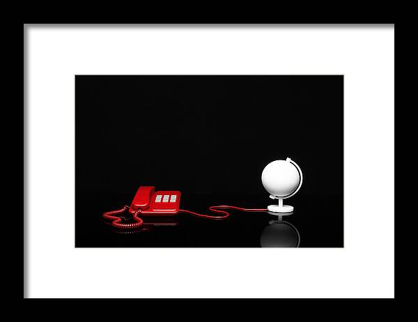 Empty Framed Print featuring the photograph A telephone is connected to a desk globe via a cable by Creative Crop