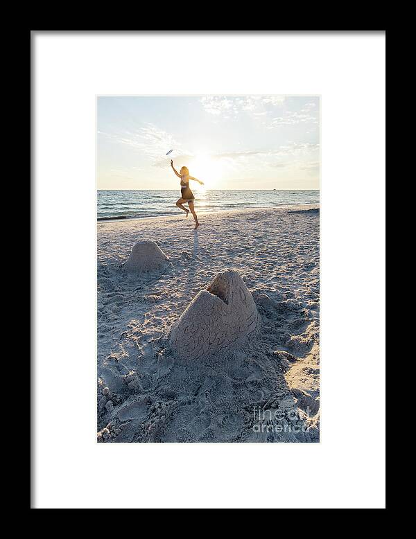 Anna Maria Island Framed Print featuring the photograph A woman catches a flying disk near a sand sculpture of a fish he by William Kuta