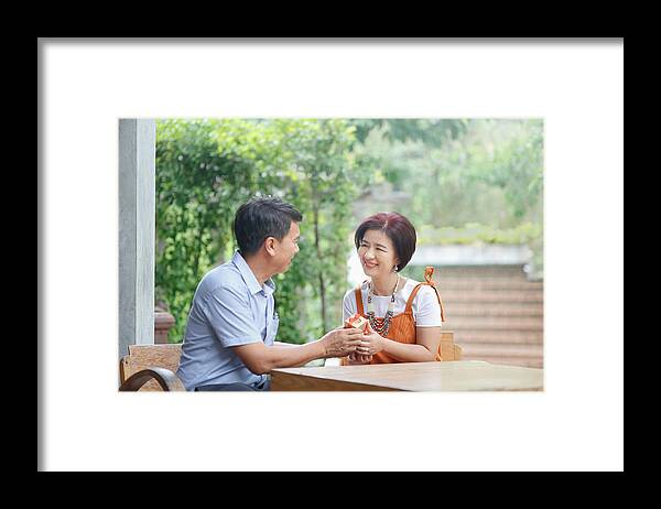 Simple Living Framed Print featuring the photograph Asian middle-aged man gives a present to his wife in anniversary wedding day by Toa55