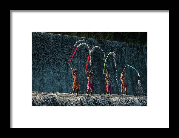 Bali Framed Print featuring the photograph Balinese boys playing with colorful slayers in the Tukad Unda waterdam by Anges Van der Logt