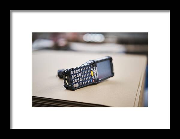Keypad Framed Print featuring the photograph Barcode scanner lying on cardbox in factory by Westend61