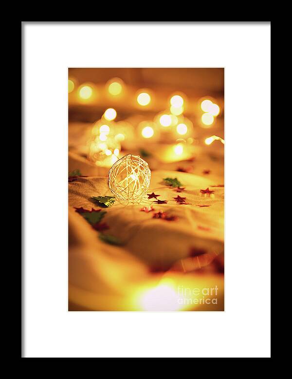 Lights Framed Print featuring the photograph Blurred golden Christmas lights with decorations on rumpled bed by Mendelex Photography