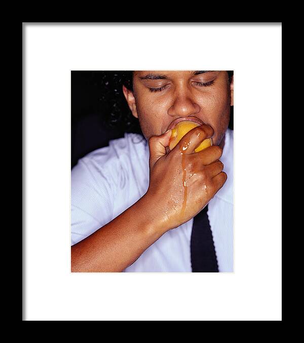 Biting Framed Print featuring the photograph Businessman biting peach, juice running down hand, close-up by Tom Merton