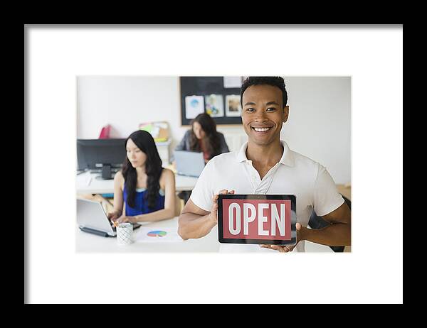 New Business Framed Print featuring the photograph Businessman holding open sign on digital tablet in office by JGI/Jamie Grill