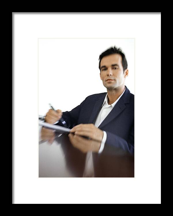 Corporate Business Framed Print featuring the photograph Businessman sitting at desk, blurred, portrait by Vincent Hazat