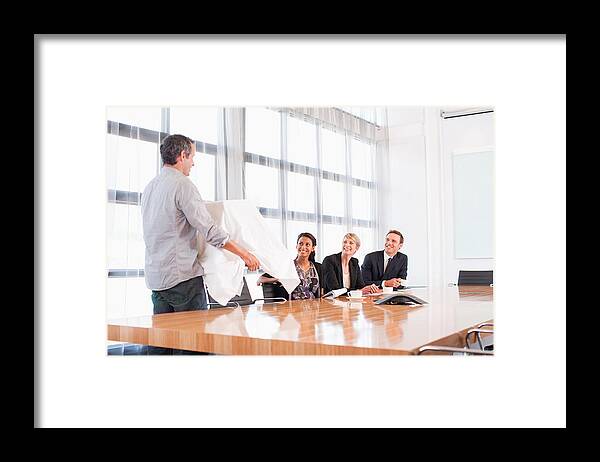 Working Framed Print featuring the photograph Businessman unveiling model building to co-workers by Martin Barraud