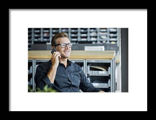 Mature Adult Framed Print featuring the photograph Businessman using mobile phone in textile factory by Morsa Images