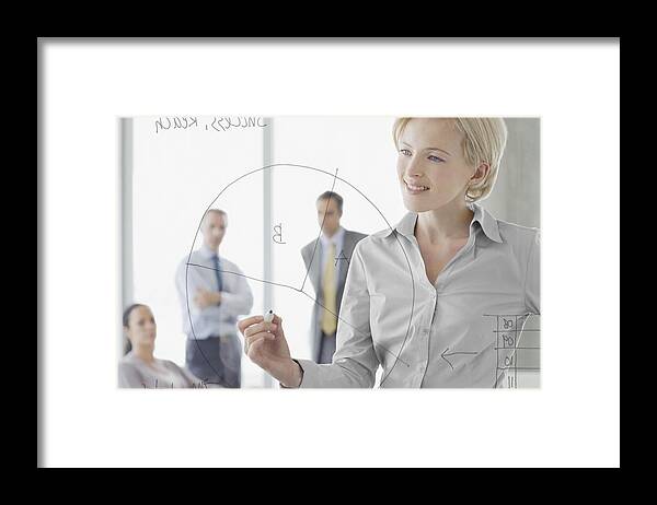 Corporate Business Framed Print featuring the photograph Businesswoman writing on glass wall in meeting by Justin Pumfrey