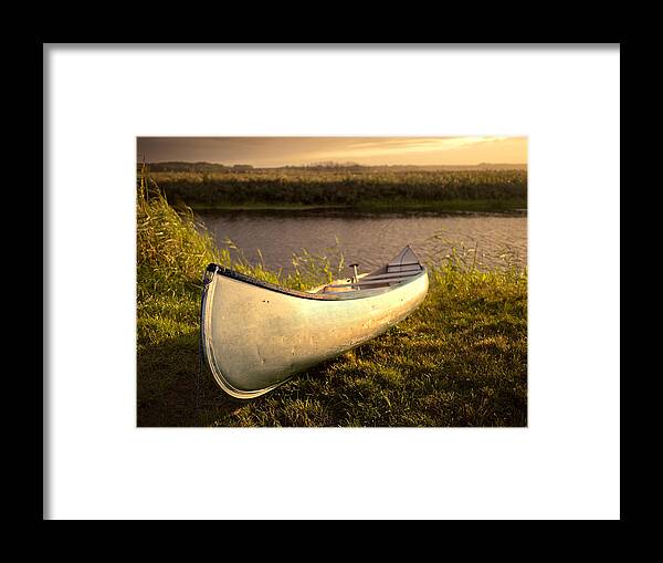 Tranquility Framed Print featuring the photograph Canoe in evening light at the river bank by Bernd Schunack