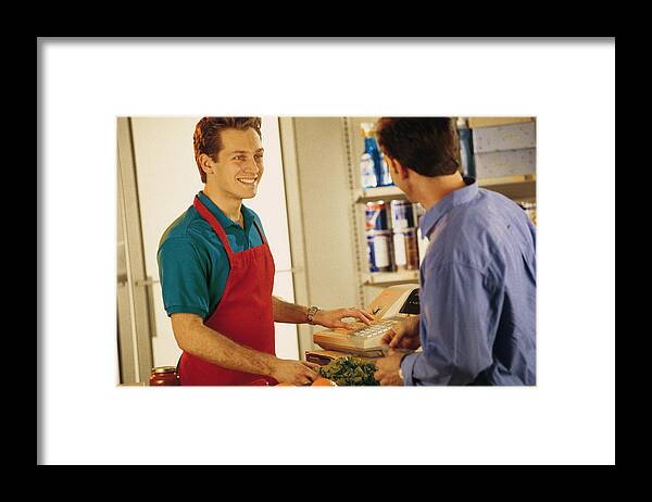 Young Men Framed Print featuring the photograph Cashier with customer at grocery store by Comstock
