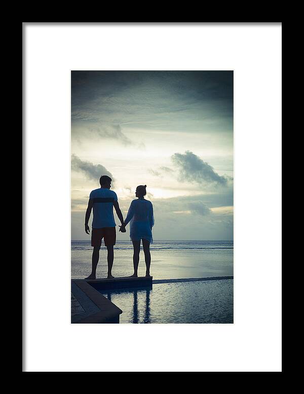 Young Men Framed Print featuring the photograph Caucasian couple holding hands near swimming pool at sunset by Jacobs Stock Photography Ltd