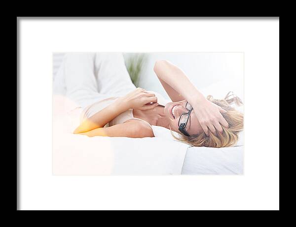 Moving To Lying Down Position Framed Print featuring the photograph Cheerful young woman on bed wearing smart glasses by Dean Mitchell