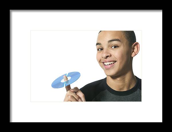 Dvd Framed Print featuring the photograph Close Up Shot Of A Teenage Male As He Holds Up A Cd On His Finger by Photodisc