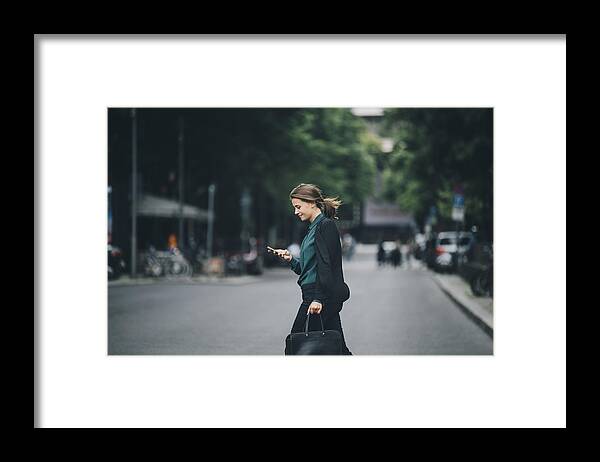 Internet Framed Print featuring the photograph Confident businesswoman using smart phone while crossing street in city by Maskot