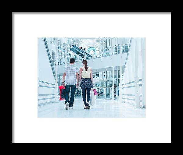 Heterosexual Couple Framed Print featuring the photograph Couple carrying shopping bags in mall by Martin Barraud