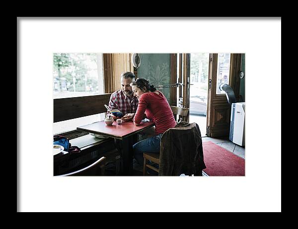 Heterosexual Couple Framed Print featuring the photograph Couple in Cafe reading Tour Guide by Hinterhaus Productions