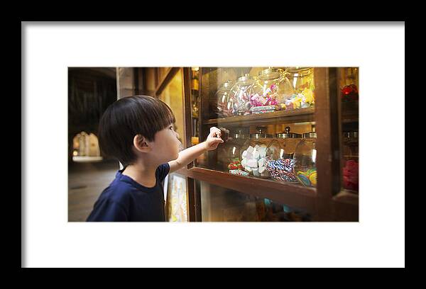 4-5 Years Framed Print featuring the photograph East asian young boy looking at colourful candy jars. by Twomeows