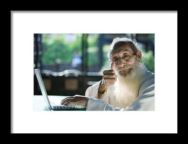 Internet Framed Print featuring the photograph Elderly man wearing traditional Chinese clothing, using laptop, giving thumbs up to camera by ZenShui/James Hardy