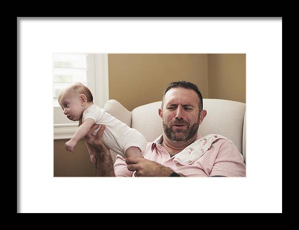 Mature Adult Framed Print featuring the photograph Father holding baby with dirty diaper by The Good Brigade